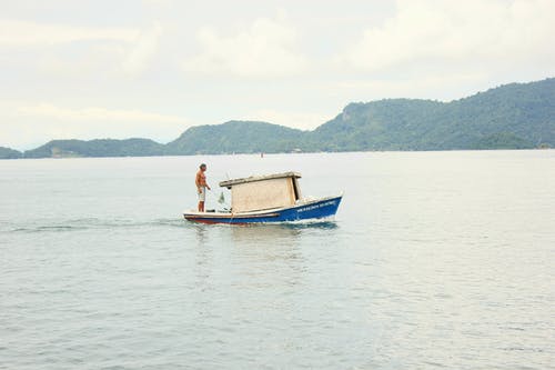不可识别的渔夫在船上用杆在湖上捉鱼 · 免费素材图片