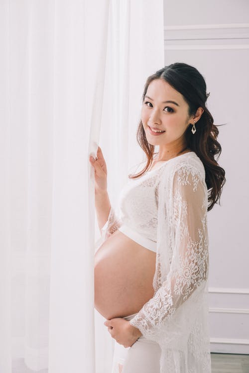 亚洲孕妇站在白色的窗帘附近 · 免费素材图片