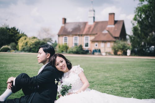 美满的新婚亚洲夫妇在舒适的豪宅的草地上休息 · 免费素材图片