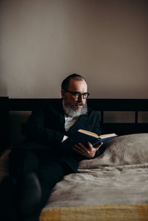 躺在床上看书有胡子的人 · 免费素材图片