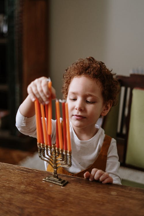男孩把蜡烛放在烛台 · 免费素材图片