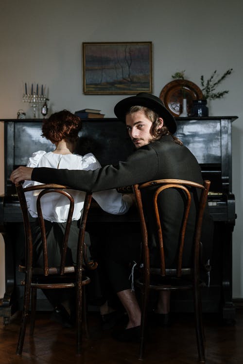 黑色外套坐在棕色木椅上的女人 · 免费素材图片