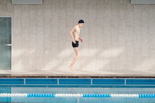 黑色短裤在游泳池上跳跃的人 · 免费素材图片