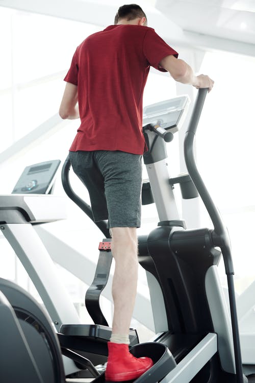 红色的t恤和黑色的短裤，站在跑步机上的男人 · 免费素材图片