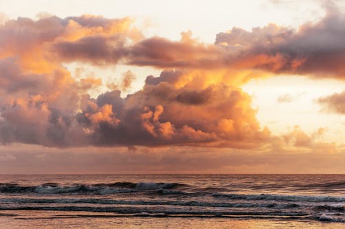 波浪之上的蓬松日落云 · 免费素材图片