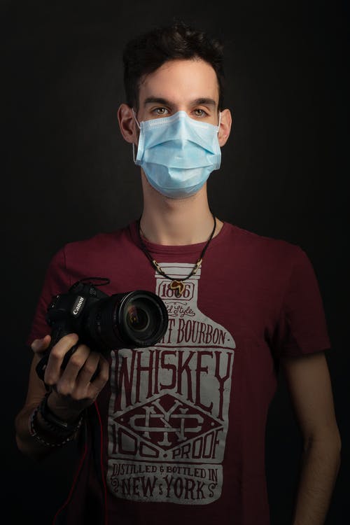 拿着红色的单反相机的红色圆领t恤的男人 · 免费素材图片