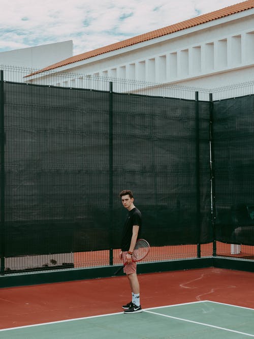 黑色衬衫站在红色和白色的网球场上的男人 · 免费素材图片