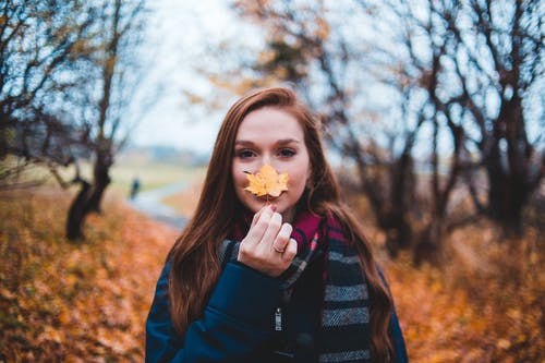 女人拿着枫叶的照片 · 免费素材图片