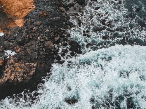水浪击中棕色岩石 · 免费素材图片