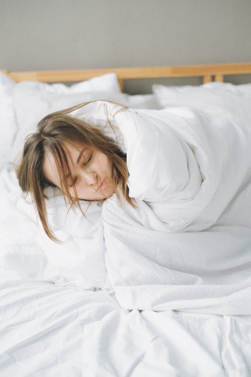 女人躺在白色的毯子，躺在床上 · 免费素材图片
