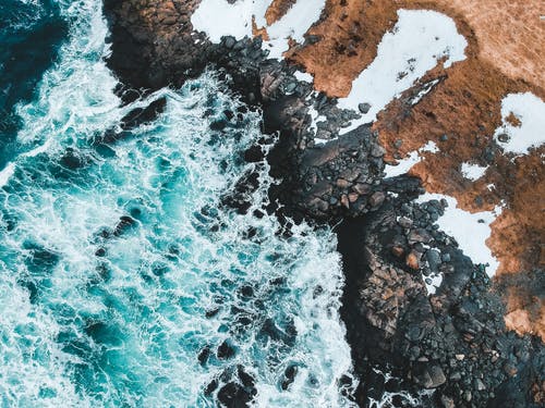 海浪撞击多岩石的海岸的鸟瞰图 · 免费素材图片