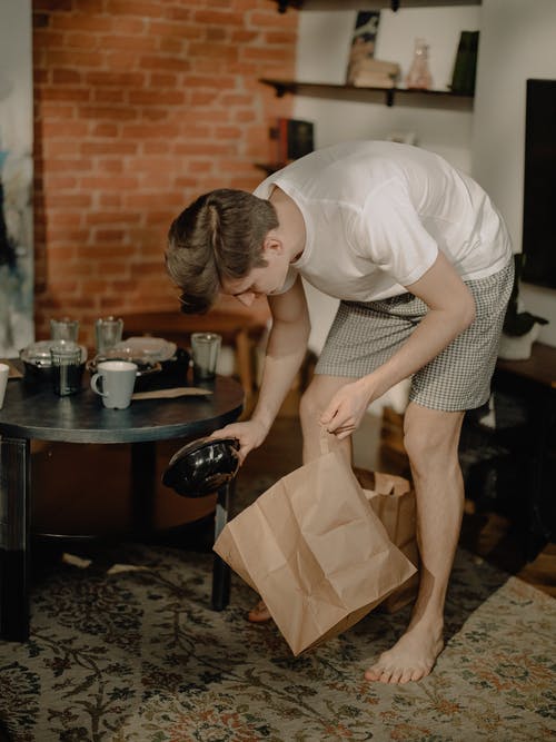 拿着棕色纸袋的白色t恤和黑色和白色圆点裙的女人 · 免费素材图片