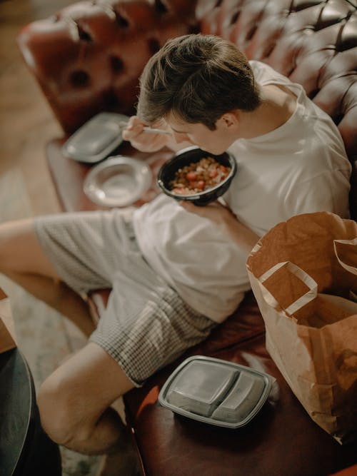 白色的t恤和棕色的裤子，坐在棕色的木椅上的男人 · 免费素材图片