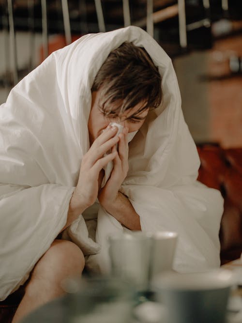 一个生病的人用纸巾擦鼻子 · 免费素材图片