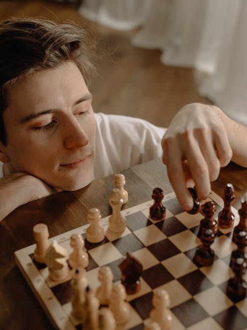 拿着棋子的白色长袖衬衫的女人 · 免费素材图片