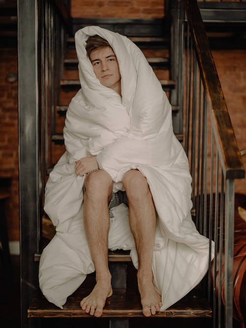 白色头巾的妇女坐在棕色木楼梯 · 免费素材图片