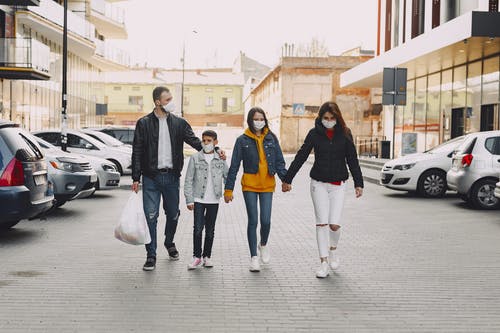 年轻的家庭，在医疗口罩走在停车场 · 免费素材图片