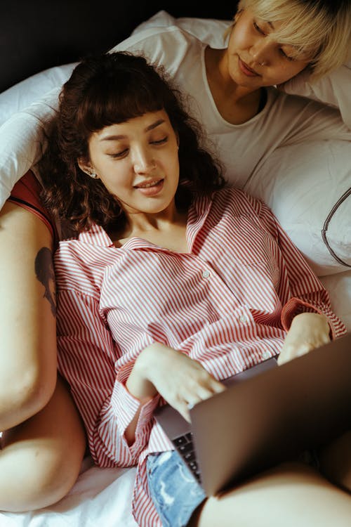 女人使用一台笔记本电脑，斜倚在她的女朋友 · 免费素材图片