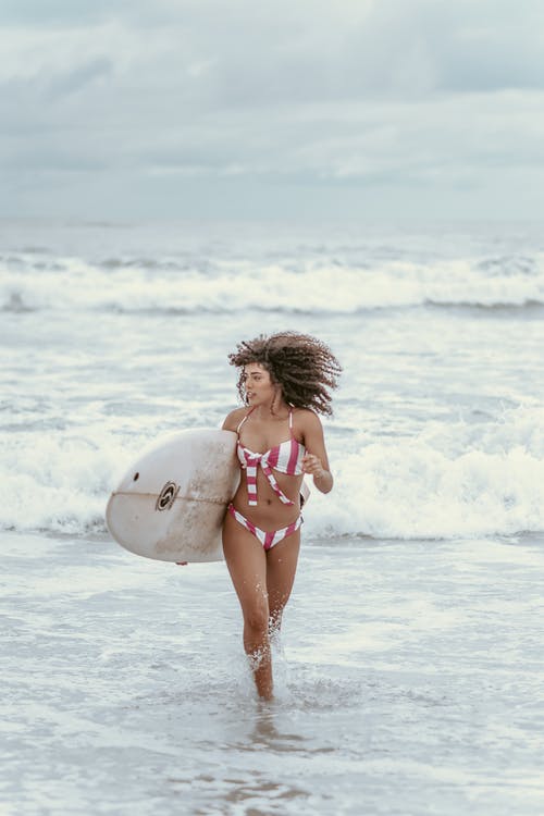 积极运动黑人女性冲浪者与冲浪板在海滩上运行 · 免费素材图片
