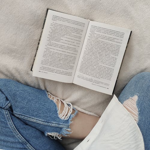 在软的床上的无法认出的妇女阅读书 · 免费素材图片