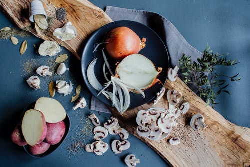 一盘生洋葱放在木板上的土豆和切碎的蘑菇 · 免费素材图片