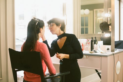 对顾客做构成的年轻女性化妆师 · 免费素材图片