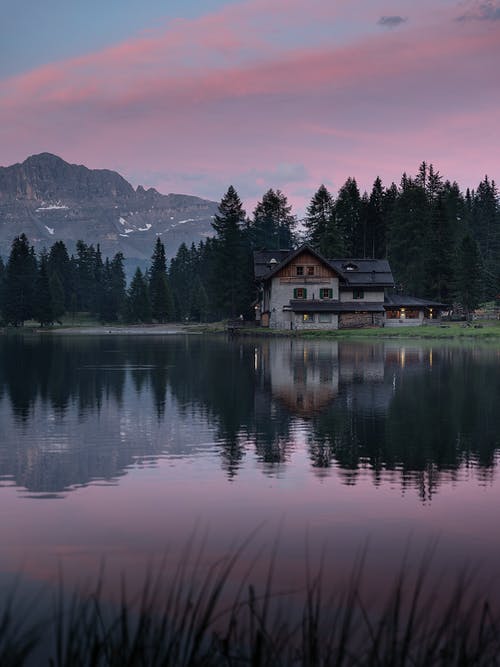 在日落时反映在山后湖中的老房子 · 免费素材图片