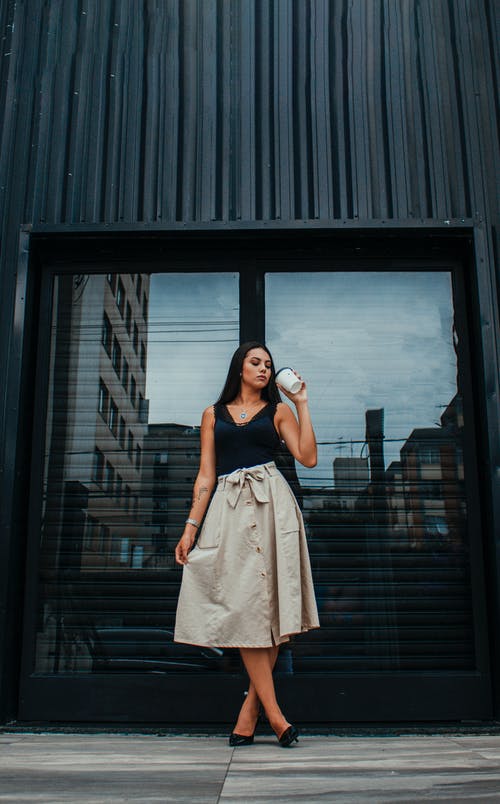 集中小姐在建筑物附近的街道上喝外卖饮料 · 免费素材图片