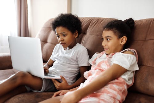 兄弟姐妹坐在沙发上，看着一台笔记本电脑 · 免费素材图片