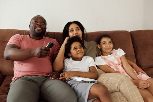 家人围坐在棕色的沙发上看电视 · 免费素材图片