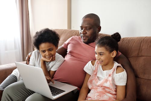 父亲和孩子们看着一台笔记本电脑 · 免费素材图片