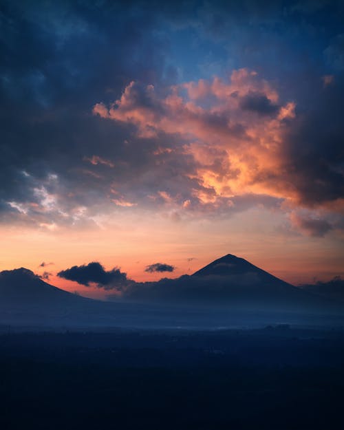 夕阳在多云的天空下山的轮廓 · 免费素材图片