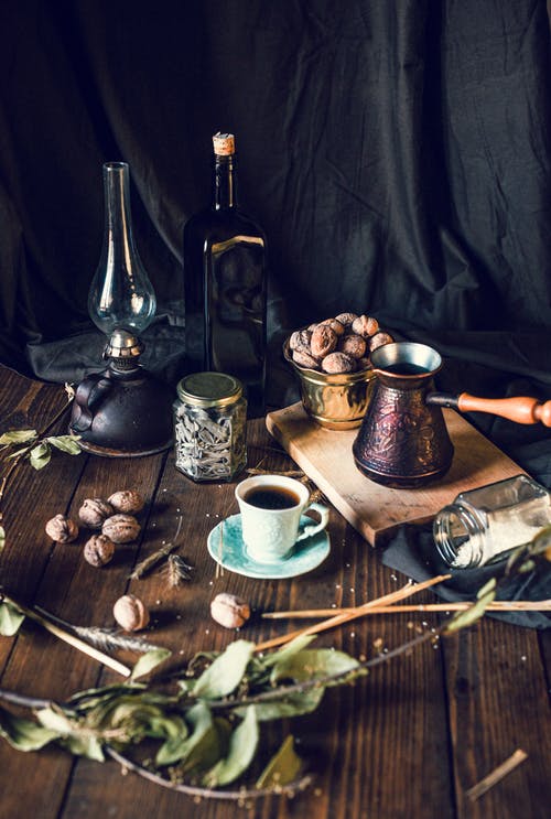 咖啡杯和壶与核桃碗放在桌上用各种香料和复古装饰品 · 免费素材图片
