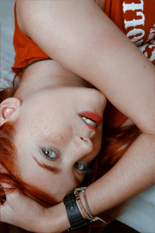 躺在床上的橙色衬衫的女人 · 免费素材图片