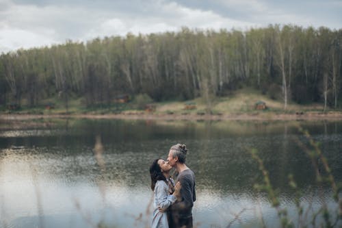 夫妇在湖附近站在一起 · 免费素材图片