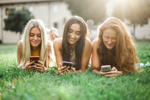 浏览智能手机在草坪上的女性朋友 · 免费素材图片