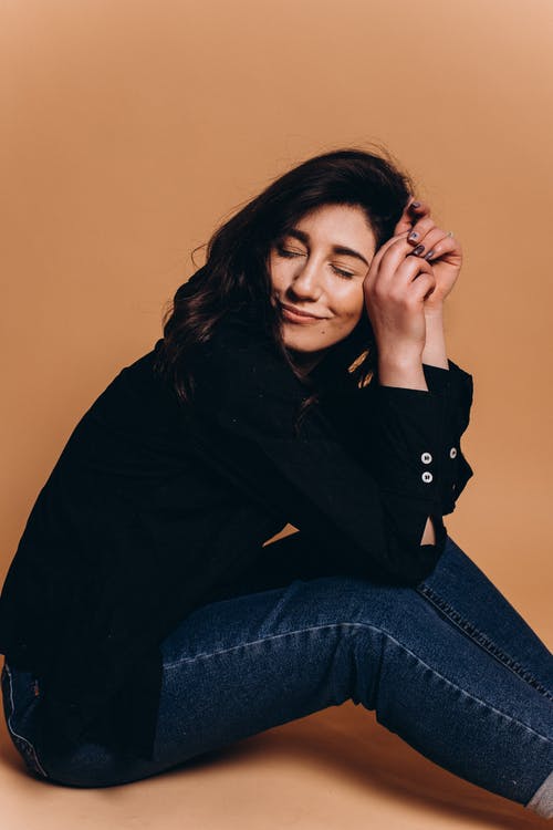 愉快的少妇坐地板在有闭合的眼睛的演播室 · 免费素材图片