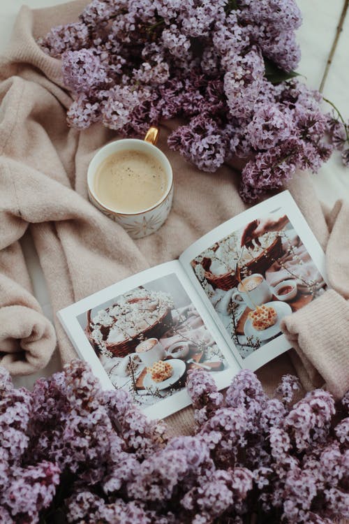 杯咖啡放在淡紫色的花附近舒适的长袍 · 免费素材图片