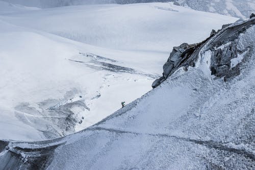 遥远的登山者在白雪皑皑的硬山坡上攀爬 · 免费素材图片