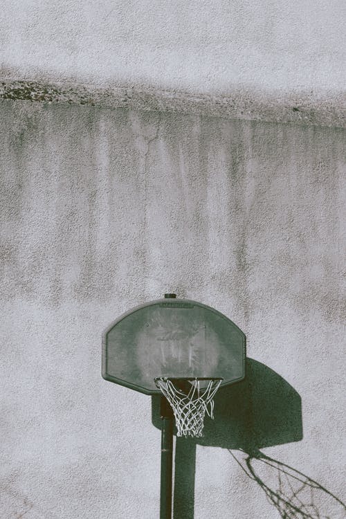 运动场上风化墙附近的篮球筐 · 免费素材图片