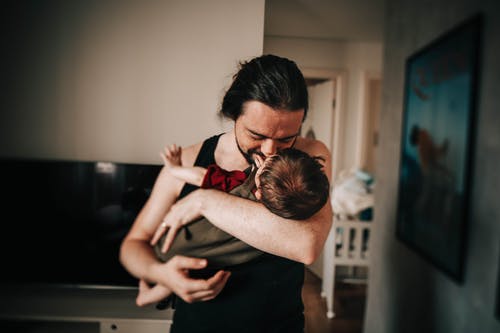 快乐的民族男人亲吻和拥抱可爱的孩子在公寓里 · 免费素材图片