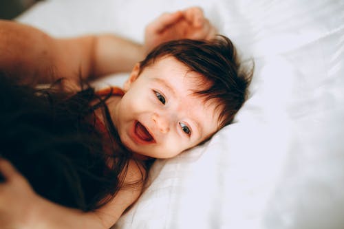 快乐婴儿和父母躺在床上玩 · 免费素材图片