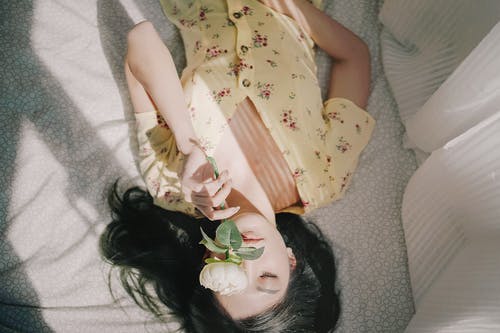 躺在床上的黄色和白色的花裙子的女孩 · 免费素材图片
