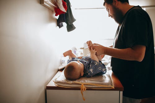 年轻的新生婴儿的父亲换尿布 · 免费素材图片