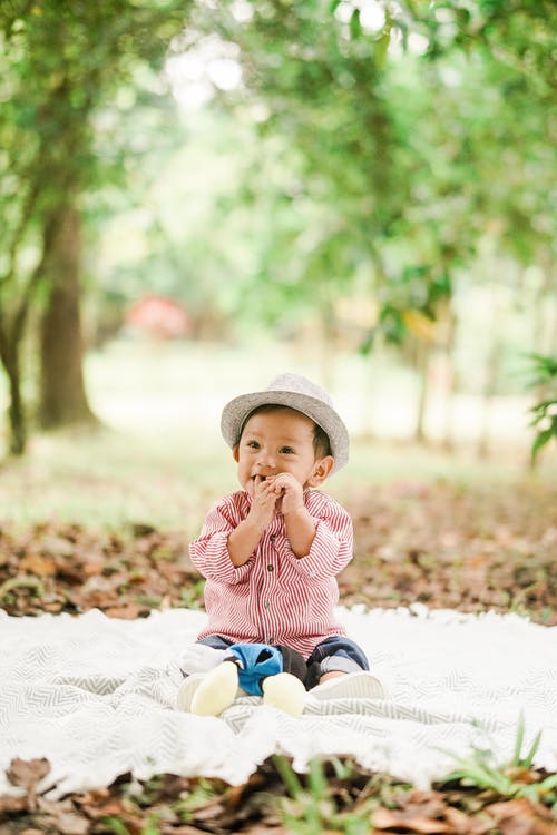 孩子坐在白色毯子上的照片 · 免费素材图片