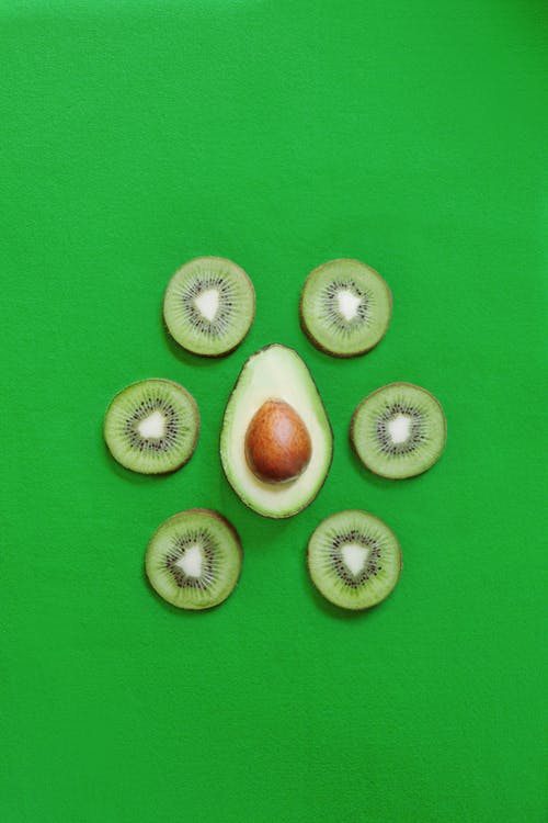 一半的鳄梨安排与猕猴桃在绿色背景上 · 免费素材图片