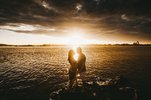 恩爱的夫妻，在日落时在海边 · 免费素材图片