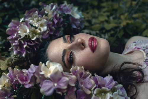 女人躺在紫色的小花场 · 免费素材图片