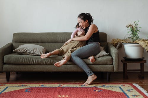拥抱她的孩子时坐在沙发上的女人的照片 · 免费素材图片