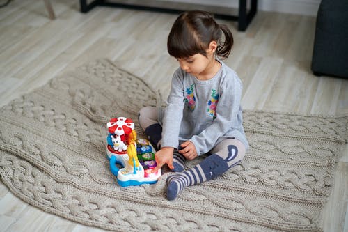 玩塑料玩具的灰色毛衣的女孩 · 免费素材图片